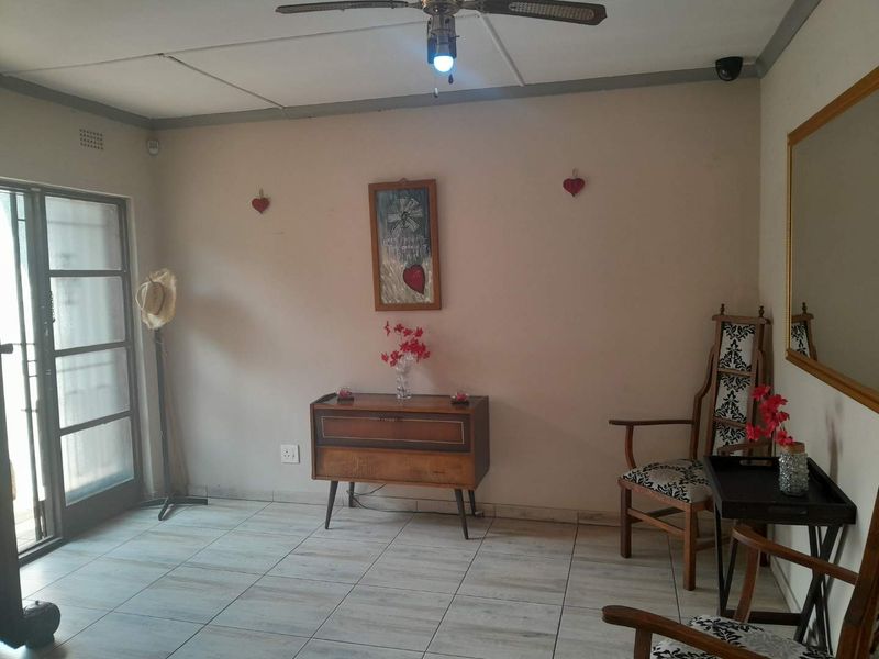 A living room area featuring tiled flooring, a ceiling fan, and a sliding glass door providing access to the exterior.