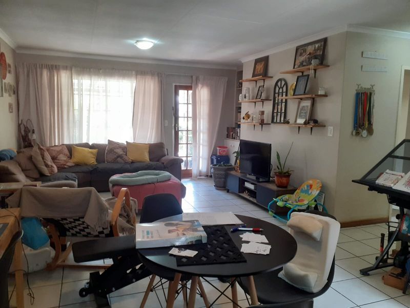 Open plan living and dining area featuring tiled flooring, built-in shelving, and direct access to the exterior through a glass panel door.