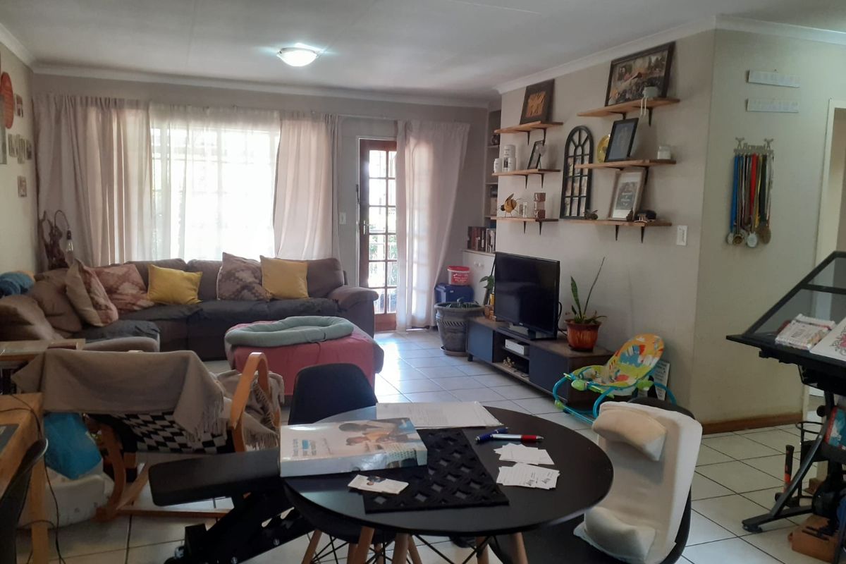 Open plan living and dining area featuring tiled flooring, built-in shelving, and direct access to the exterior through a glass panel door.