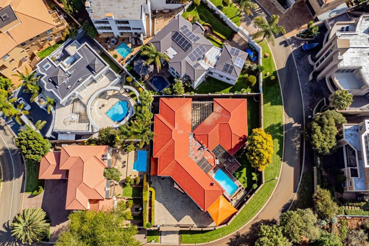 Aerial view of the property showcasing the roof layout, swimming pool, and surrounding residential neighborhood.