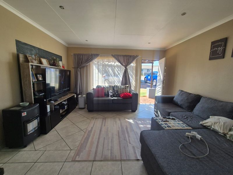 A comfortable living room featuring tiled flooring and recessed downlighting, with direct access to the exterior through a sliding door.