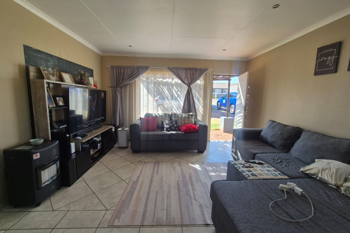 A comfortable living room featuring tiled flooring and recessed downlighting, with direct access to the exterior through a sliding door.