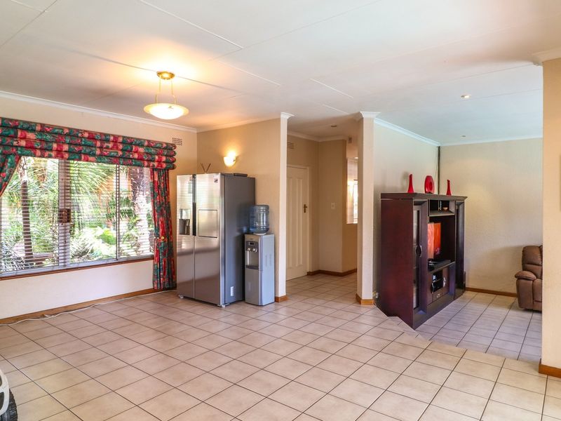 Spacious open-plan living area featuring neutral tiled flooring, recessed lighting, and a functional layout connecting to adjacent living spaces.