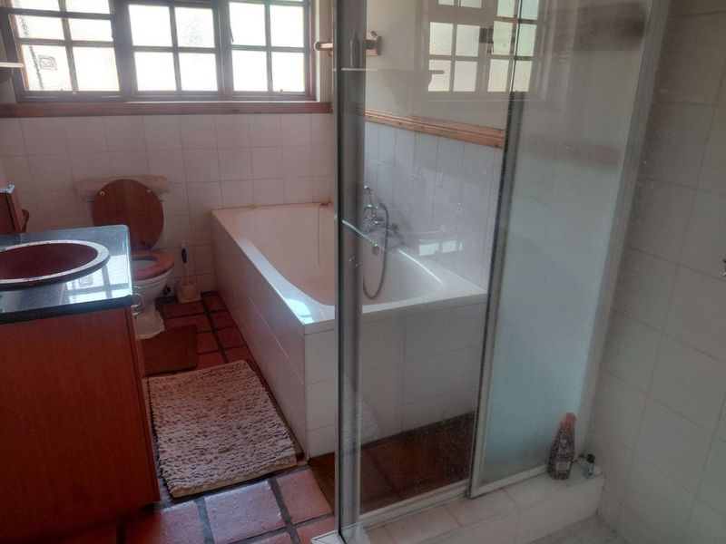 A functional bathroom featuring a built-in vanity, bathtub, separate shower enclosure, and tiled finishes throughout.