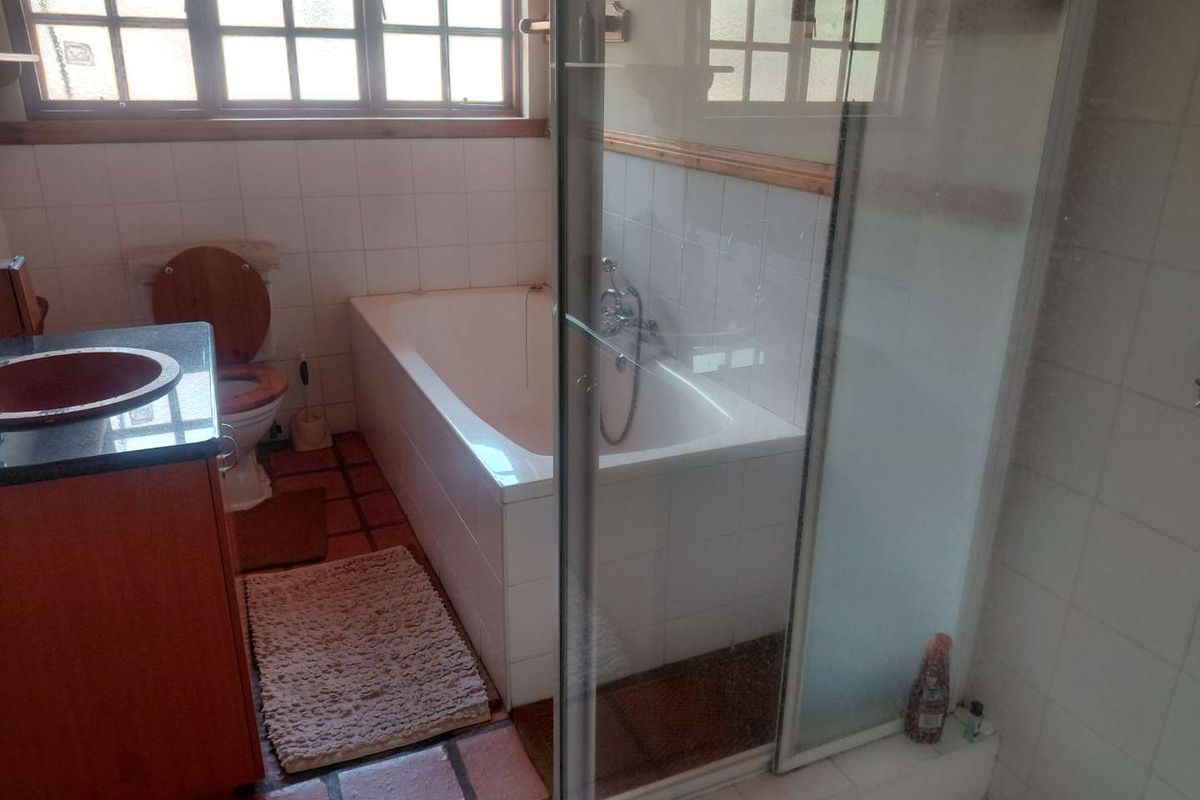 A functional bathroom featuring a built-in vanity, bathtub, separate shower enclosure, and tiled finishes throughout.