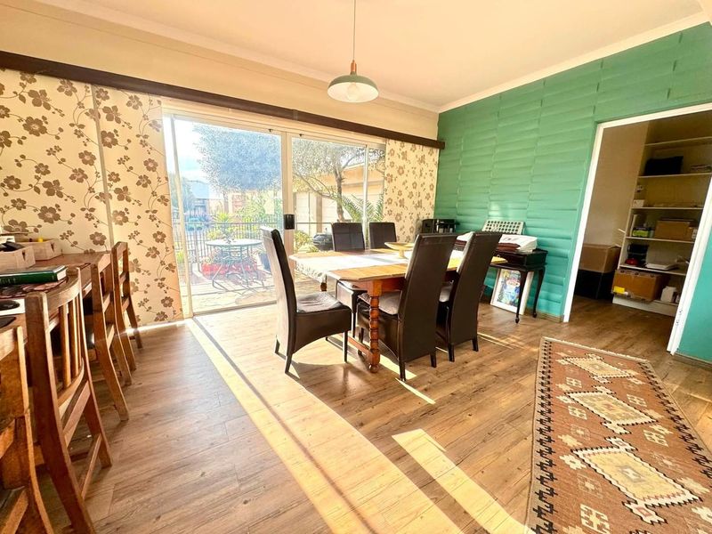 Dining area featuring laminate flooring and a large sliding glass door providing access to the outdoor patio space.