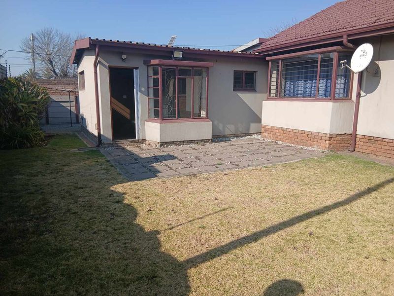 Rear view of the cottage featuring a paved patio area, bay window, and a private garden space.