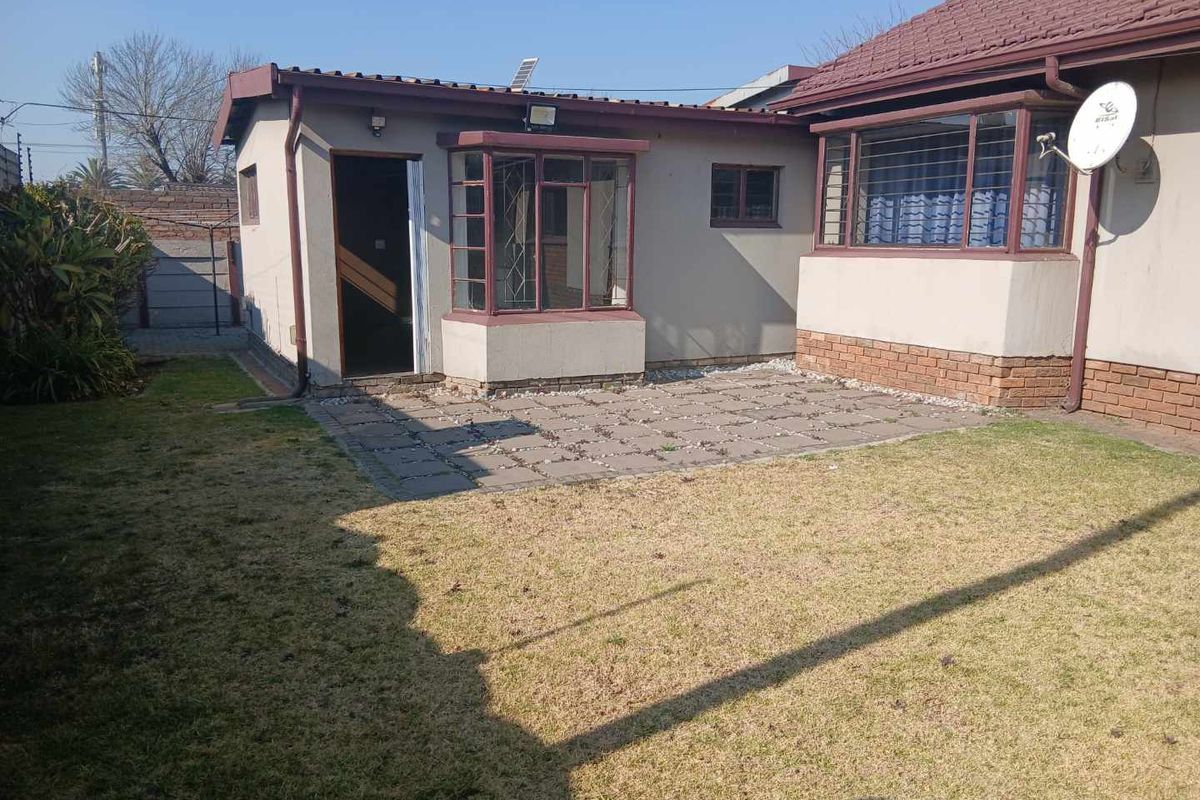 Rear view of the cottage featuring a paved patio area, bay window, and a private garden space.