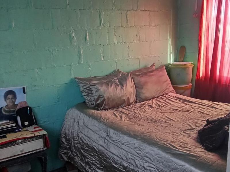 A bedroom featuring exposed concrete block walls and a simple layout, offering potential for cosmetic renovation and interior finishing.