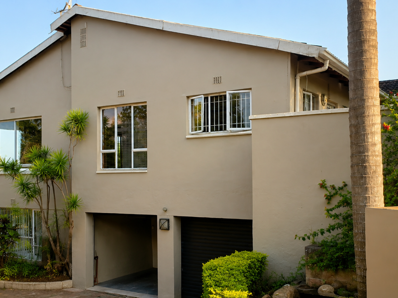 Front elevation of a multi-level residential property featuring a garage, carport, and well-maintained exterior walls with aluminium window frames.