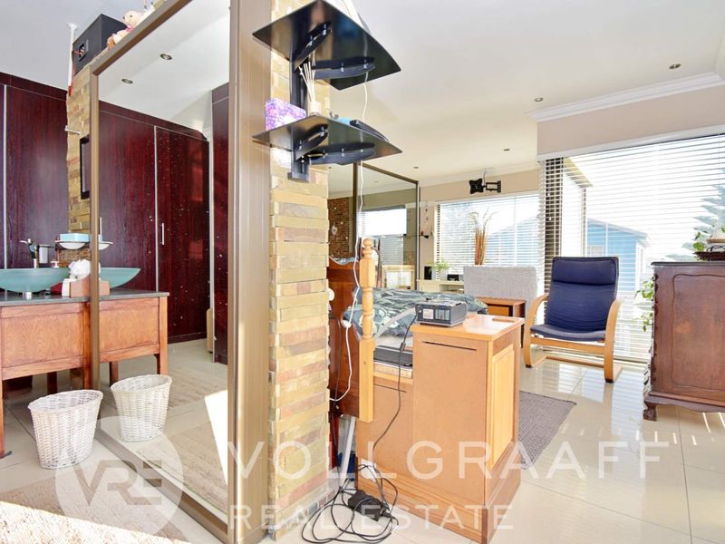Spacious bedroom featuring tiled flooring, built-in cupboards, an integrated vanity area, and large windows with venetian blinds.