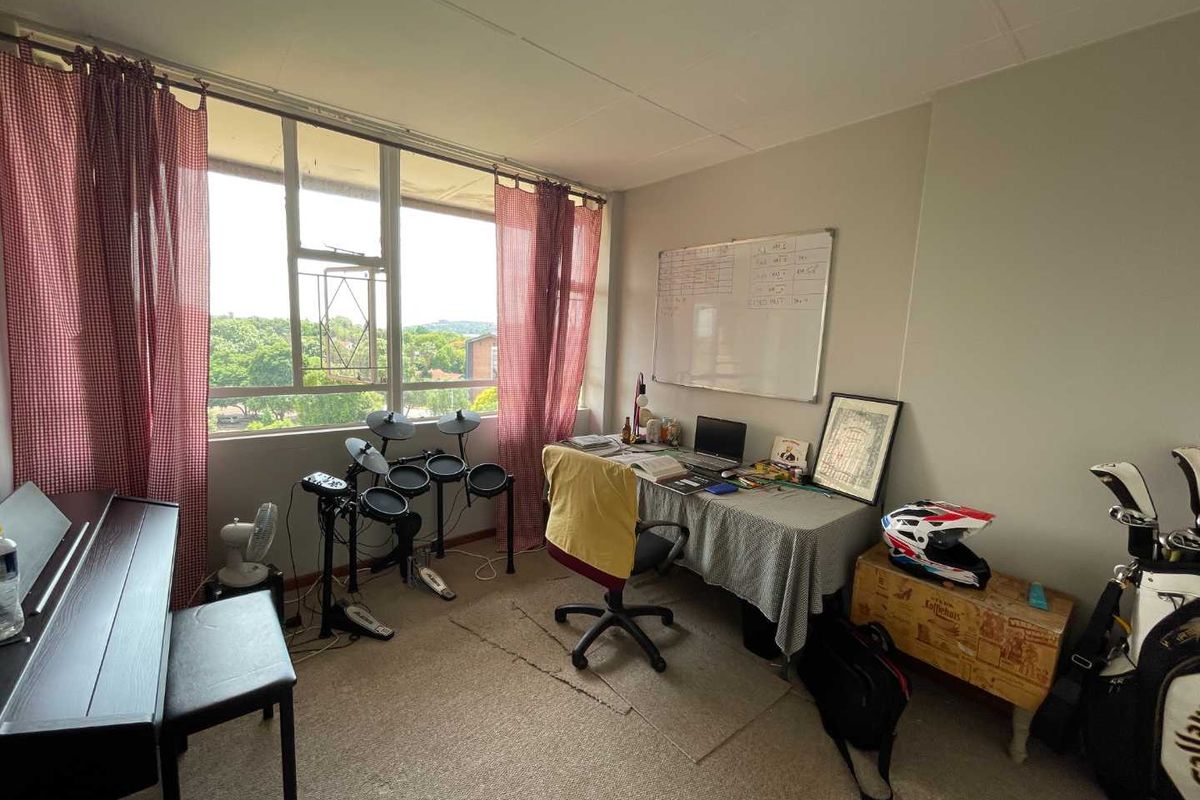 A bedroom featuring a large window with natural light and carpeted flooring, offering a functional space that could benefit from cosmetic updates.
