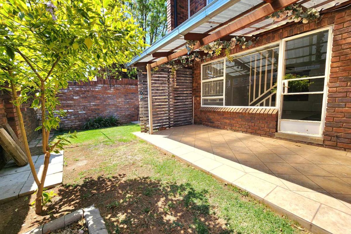 A private rear garden featuring a tiled patio area, a timber pergola, and a brick boundary wall, offering a functional outdoor space.