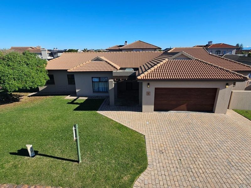 A well-maintained single-story residential home featuring a tiled roof, paved driveway, double garage, and a spacious front lawn.