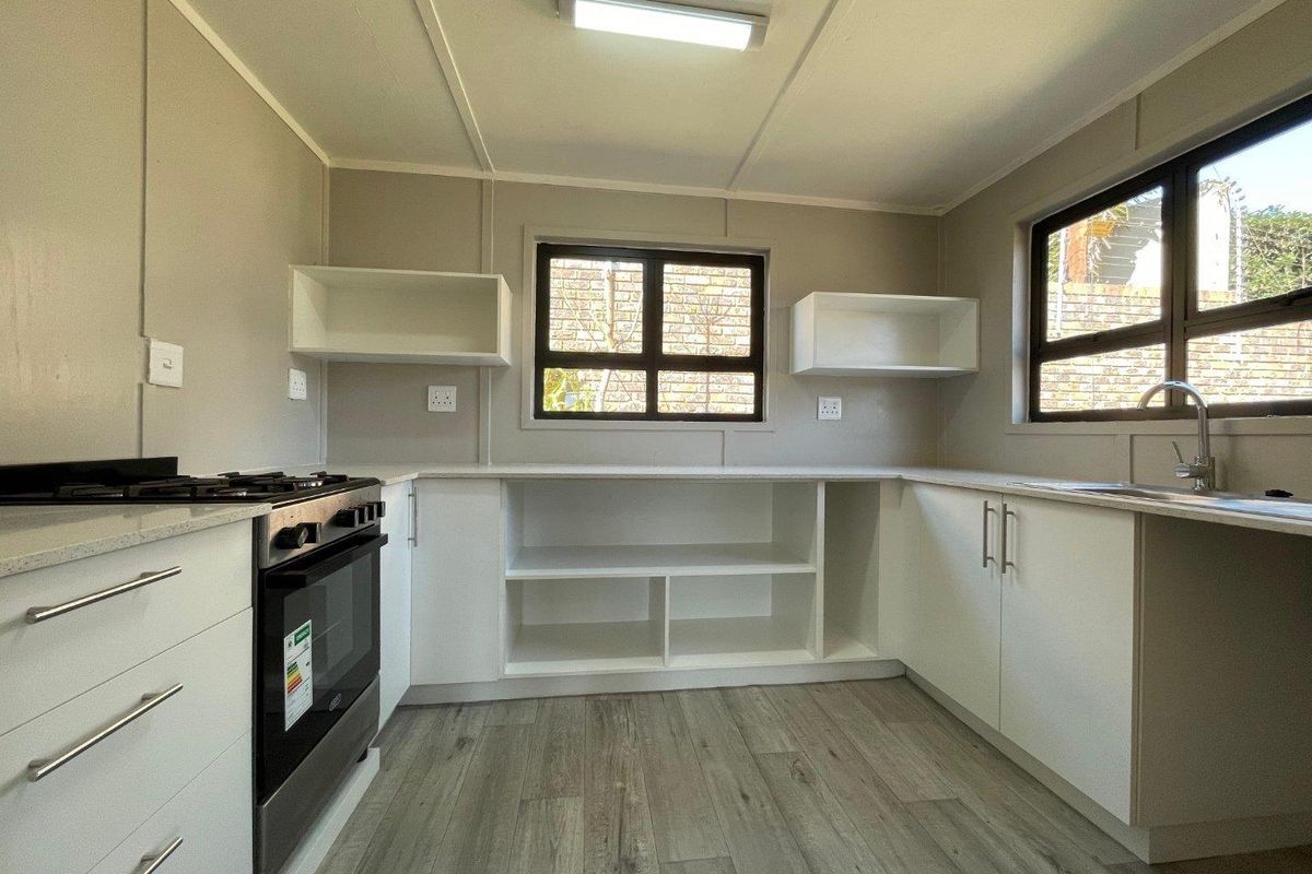 Modern kitchen featuring white cabinetry, stone-look countertops, a built-in gas stove, and wood-look laminate flooring with ample natural light.