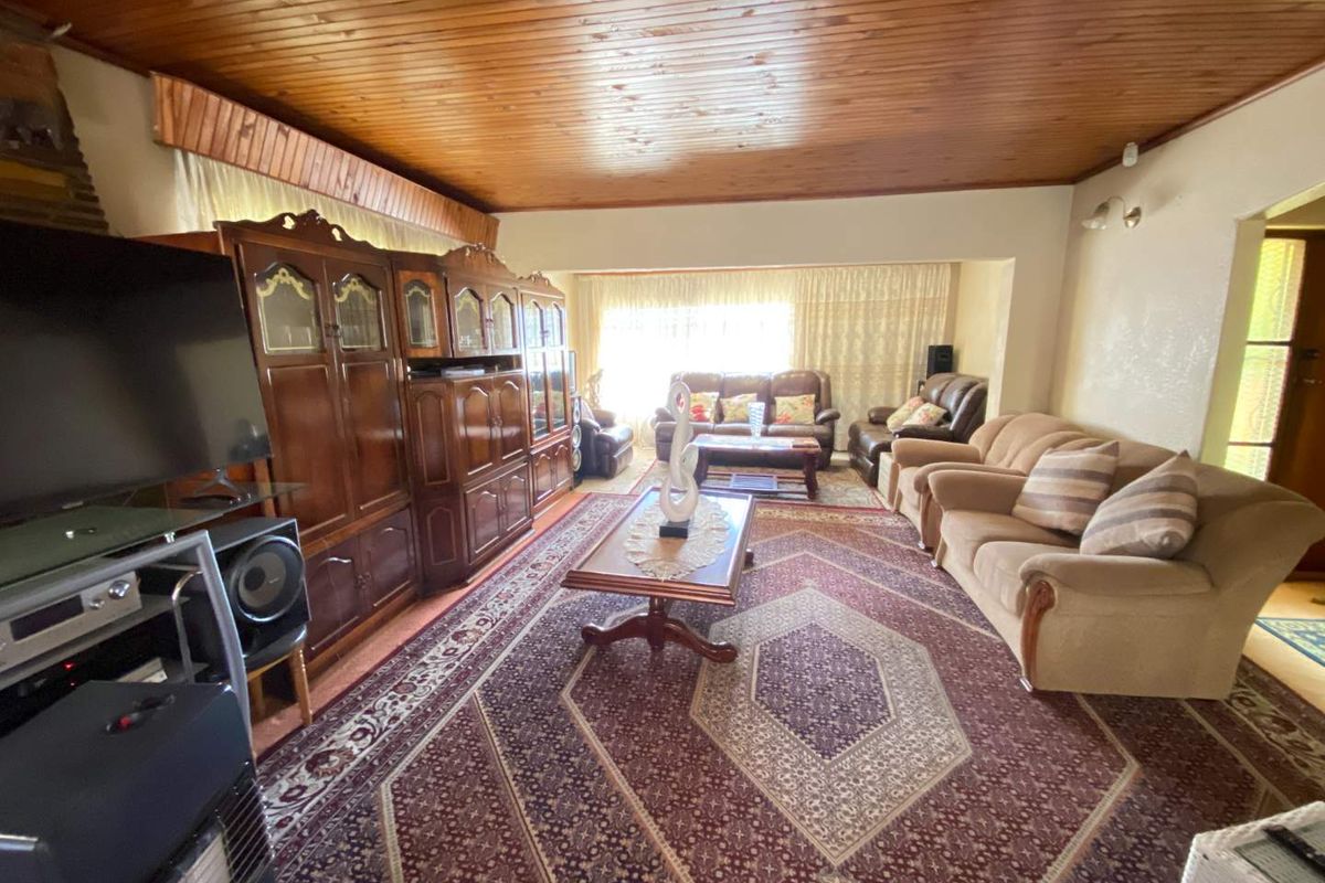 Spacious living room featuring a warm timber tongue and groove ceiling and built-in cabinetry, offering a traditional aesthetic with potential for modern updates.
