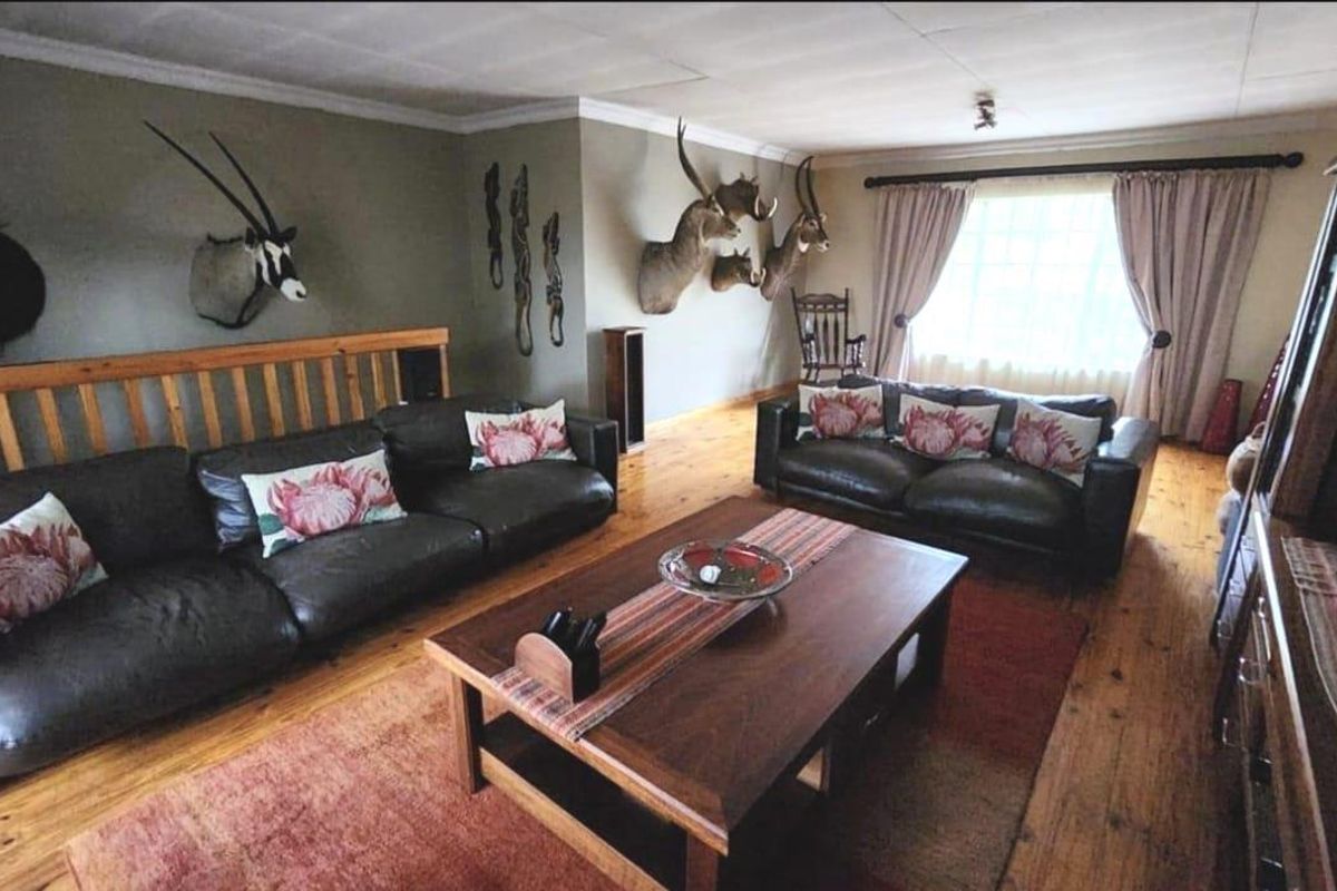 Spacious living room featuring polished timber flooring, large window with curtains, and neutral wall finishes.