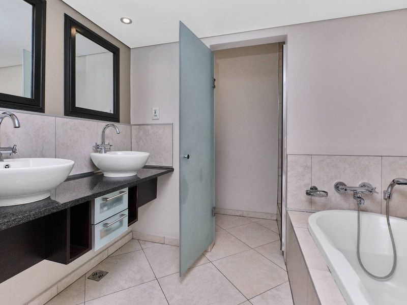 Modern bathroom featuring a double vanity with vessel sinks, granite countertop, built-in bathtub, and tiled finishes throughout.