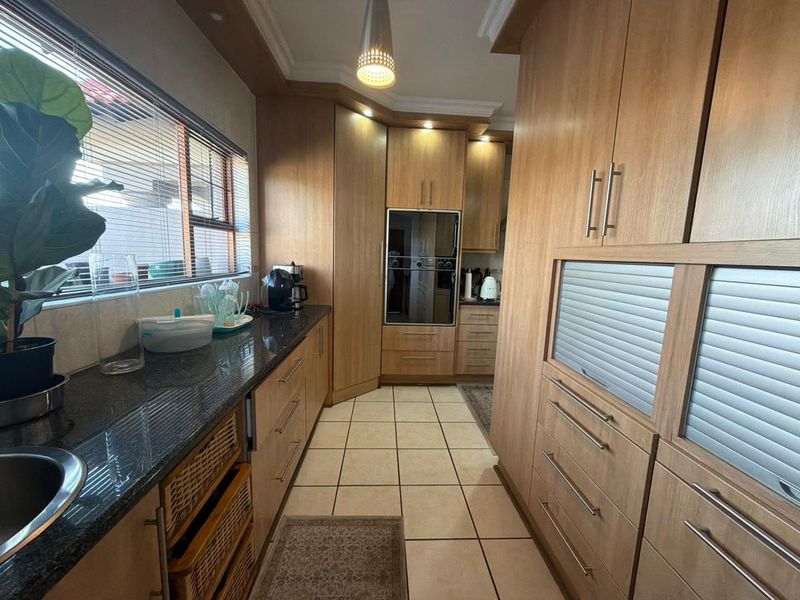 A well-maintained kitchen featuring wooden cabinetry, granite countertops, built-in oven, and tiled flooring with ample storage space.