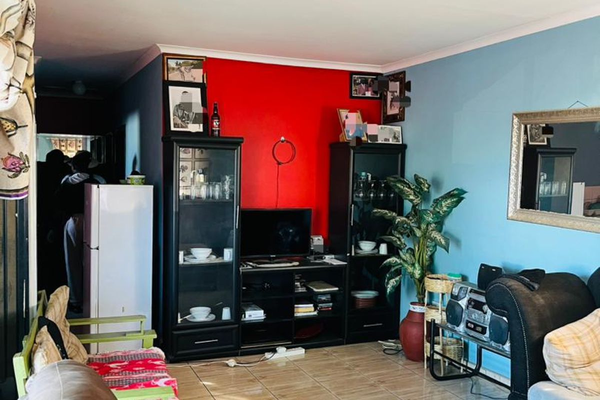 A living room featuring tiled flooring and a bold accent wall, providing a functional space with potential for modern updates.