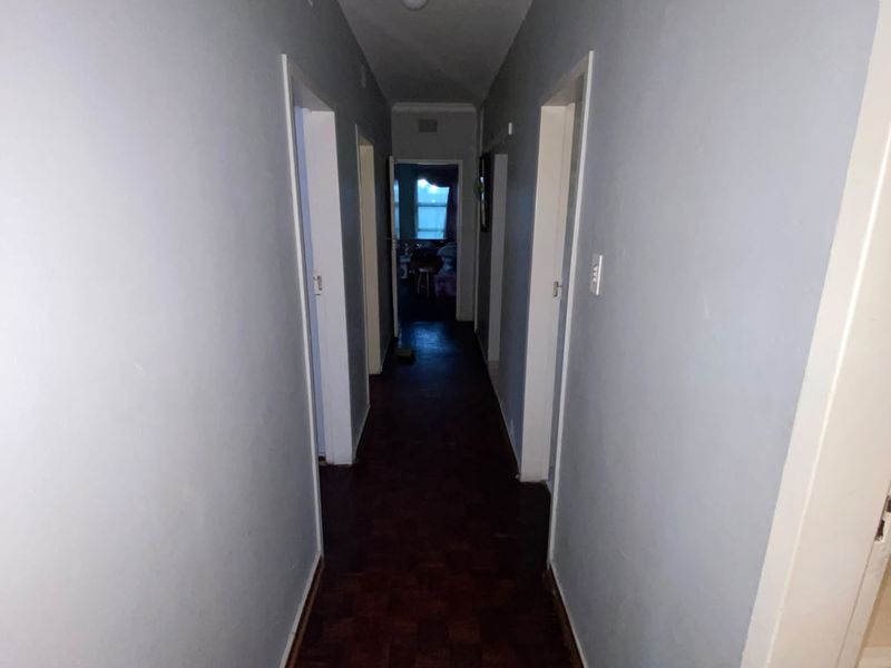 A functional interior hallway featuring traditional parquet flooring and neutral wall finishes, providing access to multiple rooms within the home.
