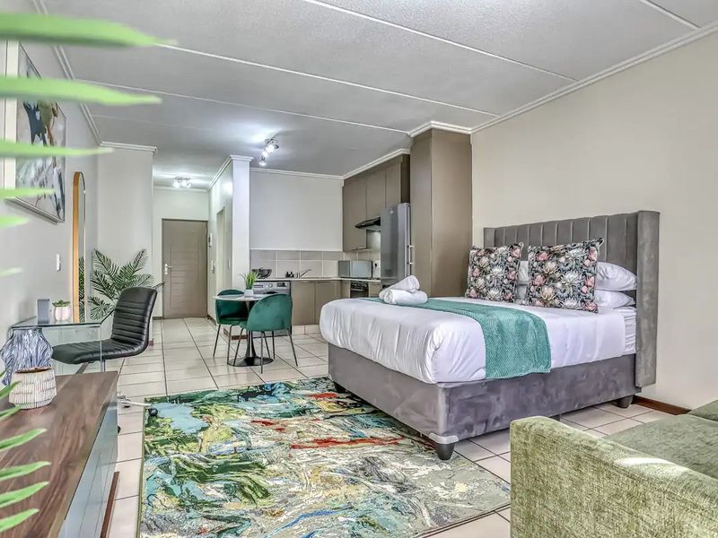 An open-plan studio apartment featuring a combined bedroom and kitchen area with tiled flooring and neutral cabinetry.