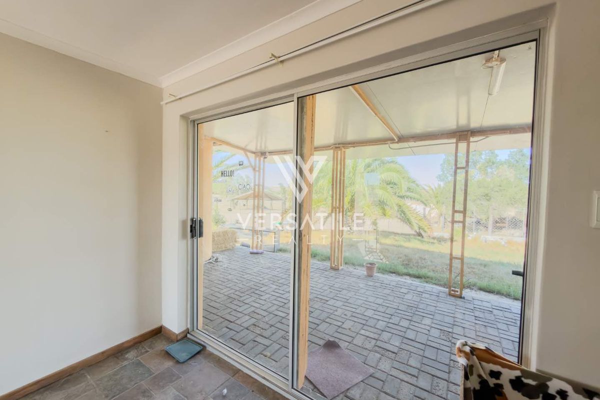 Interior view looking out through large sliding glass doors onto a paved patio area with a covered roof structure.