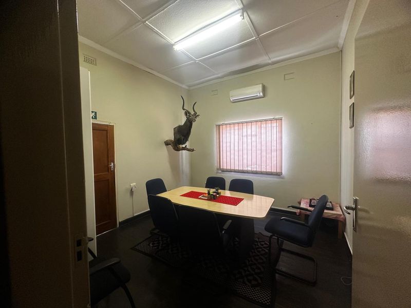 A functional office space featuring a drop ceiling, air conditioning unit, and vertical blinds, suitable for a professional work environment.