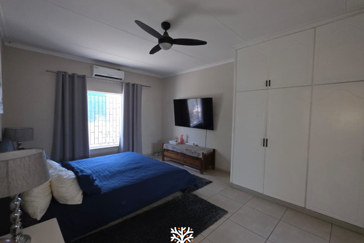 A well-maintained bedroom featuring built-in cupboards, tiled flooring, a ceiling fan, and a split-system air conditioner for climate control.