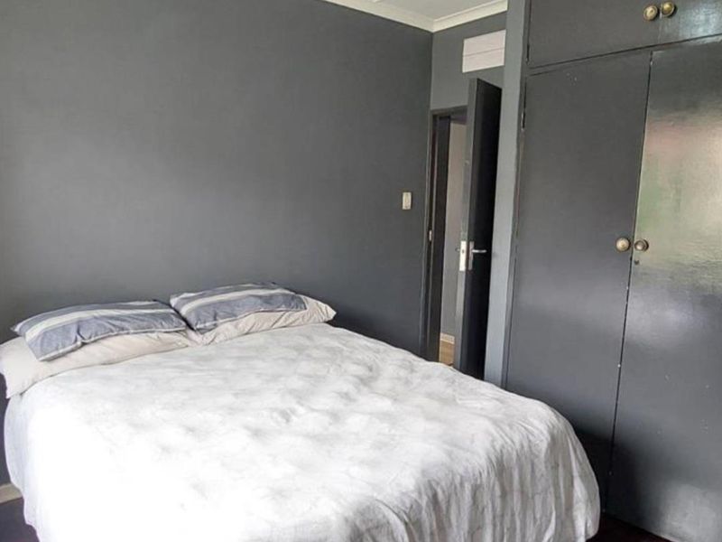 A bedroom featuring dark painted walls and a built-in wardrobe with overhead storage compartments.