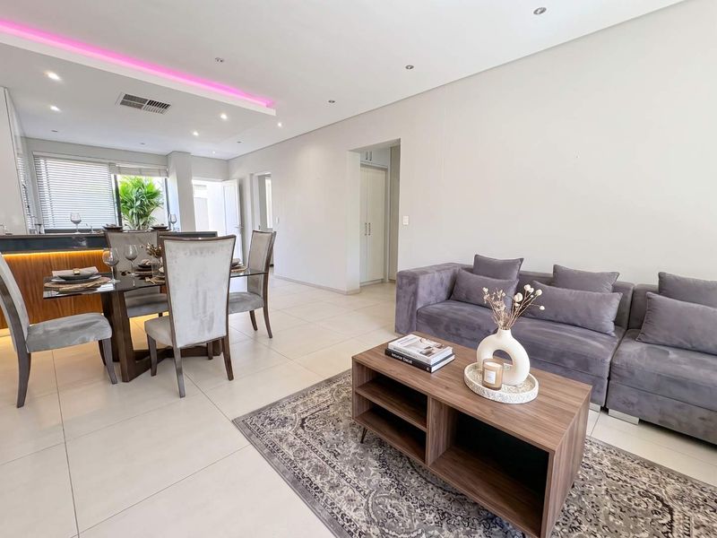 Modern open-plan living and dining area featuring sleek tiled floors, recessed ceiling lighting with ambient LED accents, and a functional kitchen island.