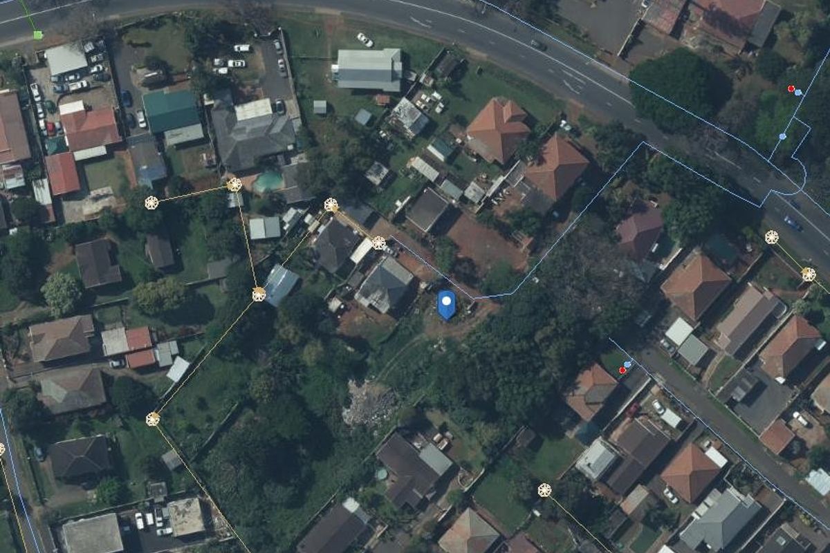 An aerial view of a residential land plot showing surrounding neighborhood context and property boundaries.