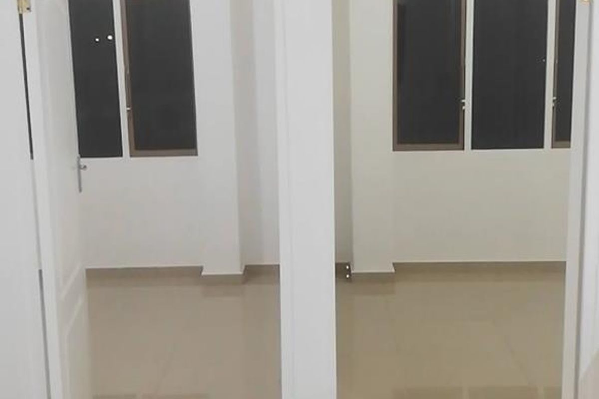 A bright, empty hallway featuring neutral tiled flooring and two doorways leading into adjacent rooms with large windows.