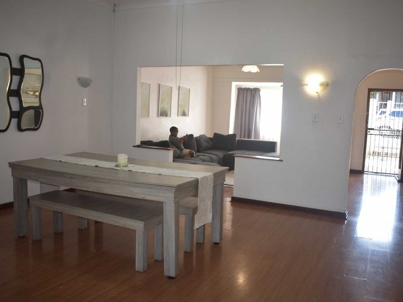Open plan living and dining area featuring laminate flooring, an arched entryway, and wall-mounted lighting fixtures.