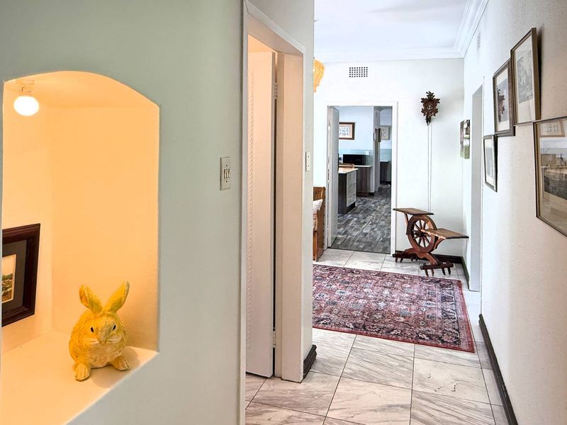 A bright hallway featuring tiled flooring, a decorative recessed wall niche, and access to adjoining rooms.