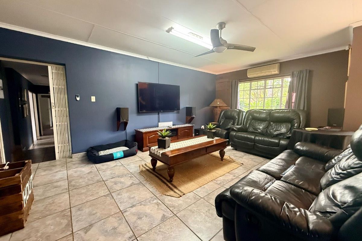 Spacious living room featuring tiled flooring, a ceiling fan, and a wall-mounted air conditioning unit.