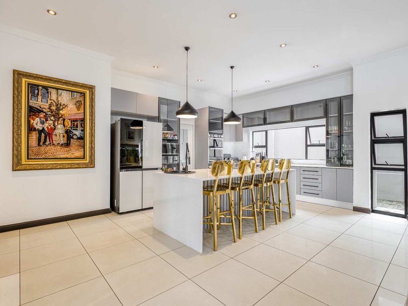 Modern, well-appointed kitchen featuring a central island with quartz countertops, sleek cabinetry, integrated appliances, and stylish pendant lighting.