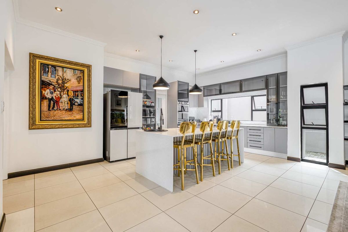Modern, well-appointed kitchen featuring a central island with quartz countertops, sleek cabinetry, integrated appliances, and stylish pendant lighting.