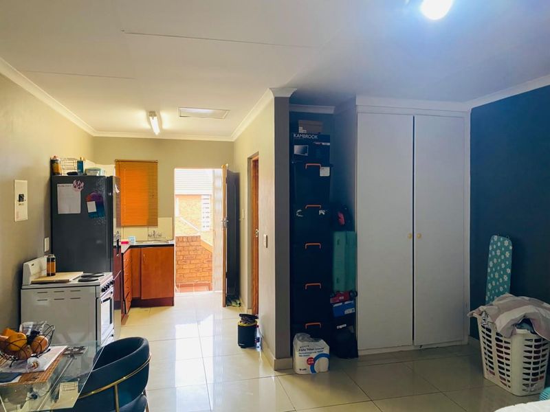 Open-plan living area featuring tiled floors, built-in storage cupboards, and a functional kitchen space with direct access to an exterior entrance.