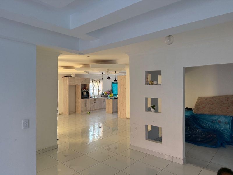 Spacious open-plan living area featuring tiled floors, recessed ceiling details, and a modern kitchen with built-in cabinetry and island.