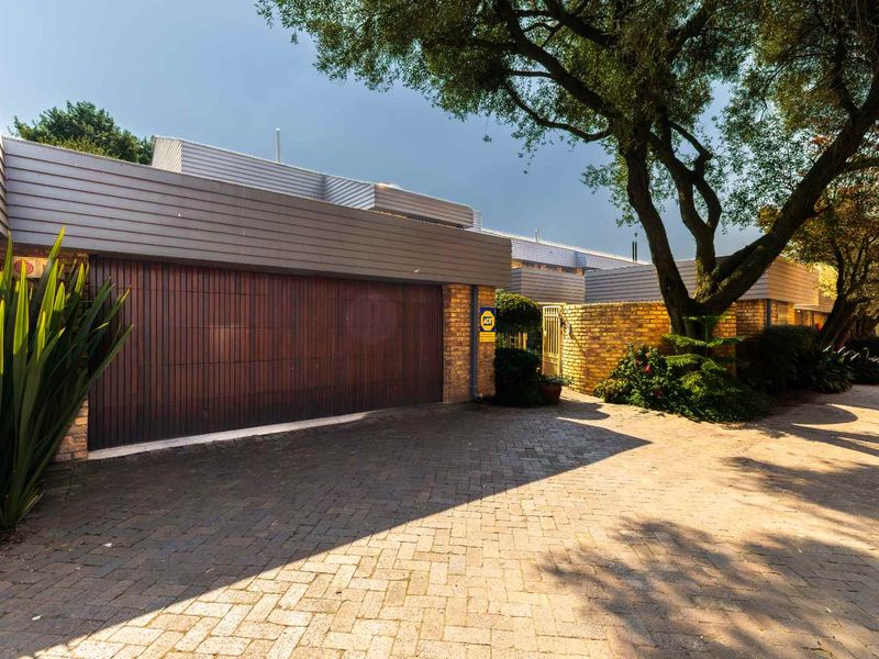 Front exterior view of the townhouse featuring a timber garage door, facebrick facade, and a paved driveway entrance.