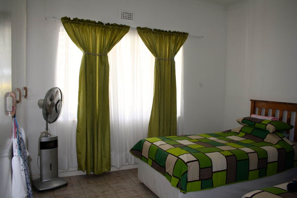 A simple bedroom featuring tiled flooring and a window with curtain fixtures.