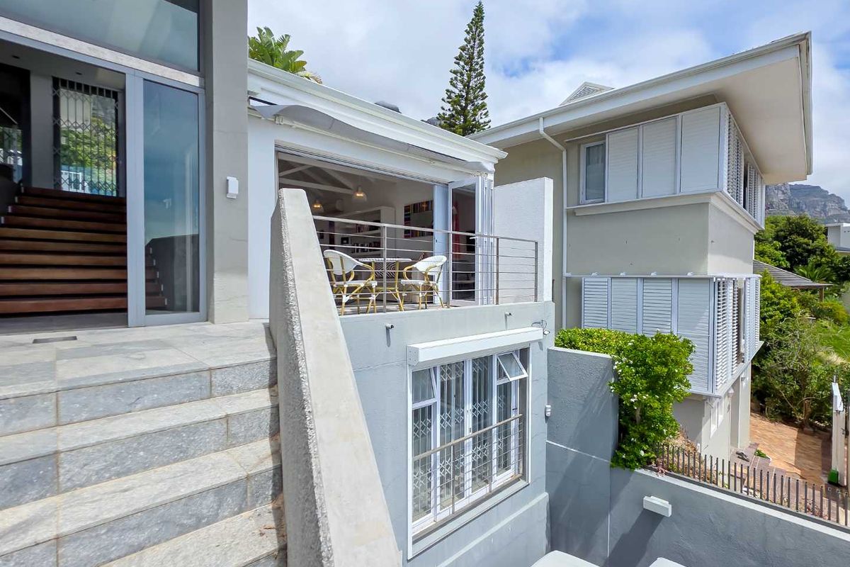 Rear exterior view of the apartment featuring a stone staircase, elevated balcony with bi-fold doors, and modern architectural finishes.
