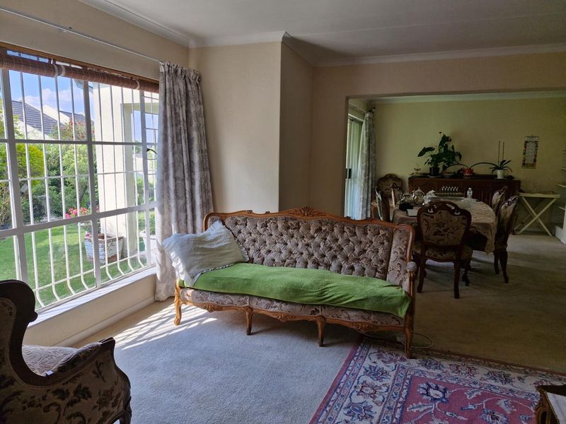 Spacious open-plan living and dining area featuring large windows with security bars, carpeted flooring, and coved ceilings, offering a bright and functional layout.