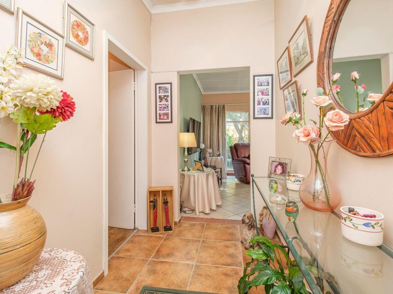 A bright, tiled hallway providing access to adjacent living spaces, featuring neutral wall tones and a clear transition between rooms.