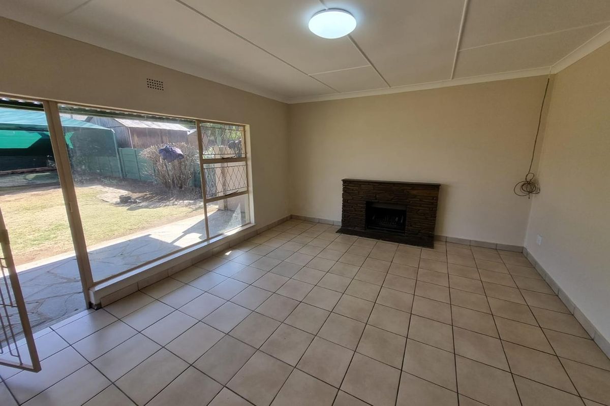 Spacious living room featuring tiled flooring, a stone fireplace, and a large sliding glass door providing direct access to the garden.