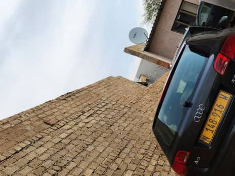 A view of the rear exterior area featuring a brick boundary wall and a satellite dish mounted on the building structure.