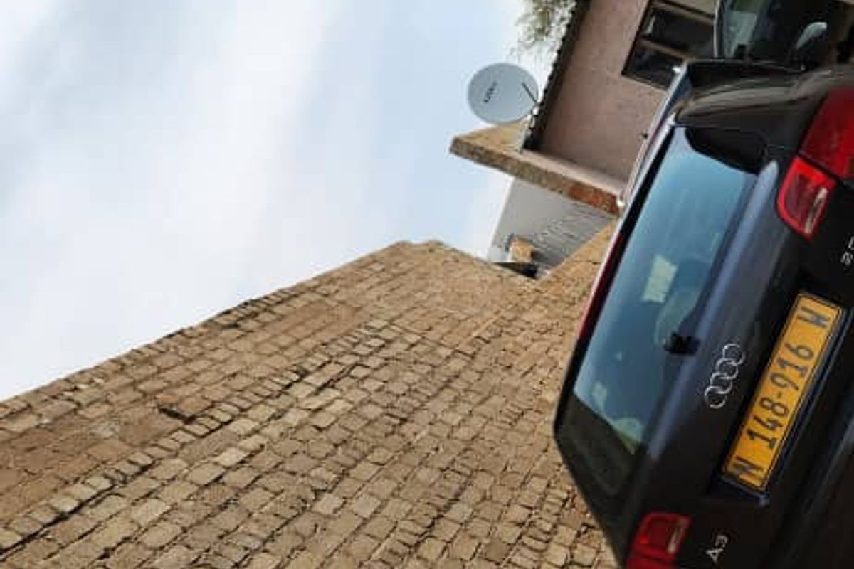 A view of the rear exterior area featuring a brick boundary wall and a satellite dish mounted on the building structure.