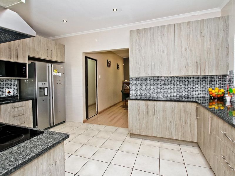 Modern kitchen featuring light wood-grain cabinetry, granite countertops, mosaic tile backsplash, and ceramic floor tiles with integrated extractor fan.
