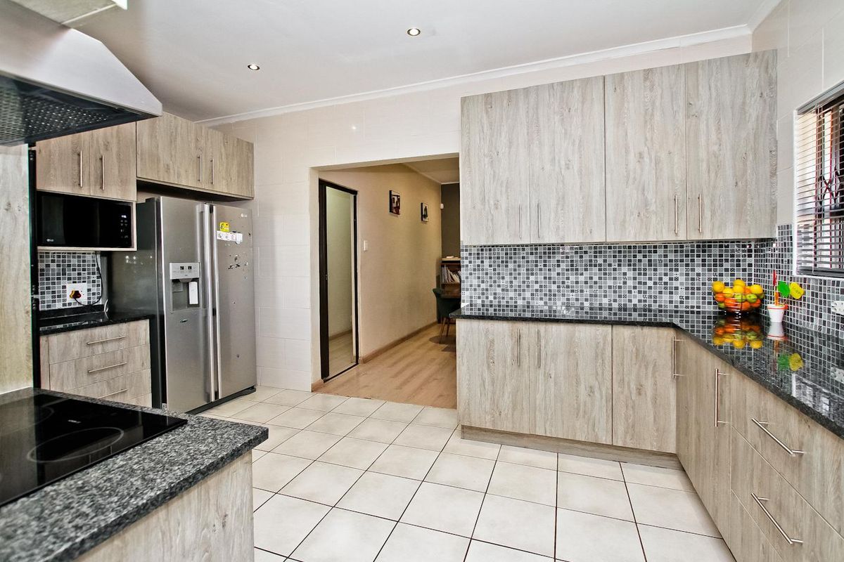 Modern kitchen featuring light wood-grain cabinetry, granite countertops, mosaic tile backsplash, and ceramic floor tiles with integrated extractor fan.
